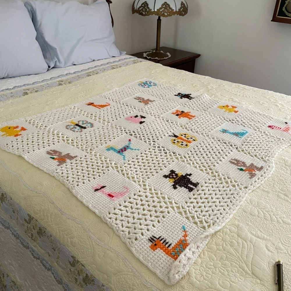 Handmade Crocheted Blanket with Cross Stitch Design, White Background.